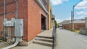 A brick building with outdoor electrical equipment, a staircase, and a clear sky. - Hogs Hideaway On Dickson St. (Fayetteville)