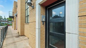 A building with a black door, a brick wall, and a metal railing. - Hogs Hideaway On Dickson St. (Fayetteville)