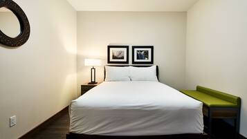 A neatly arranged bedroom with a bed, bedside table, lamp, and two framed pictures on the wall.