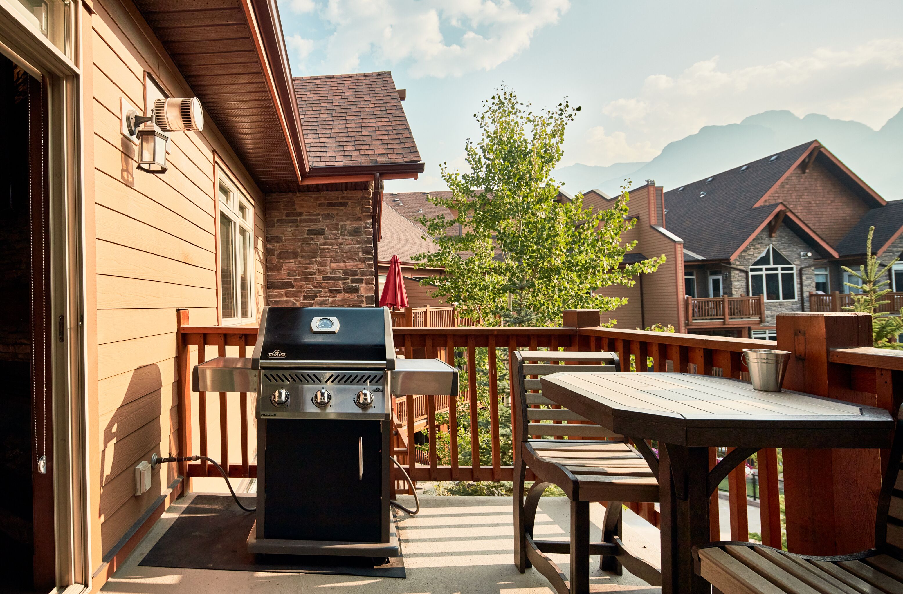 A wooden deck with a barbecue grill, a table, and chairs.