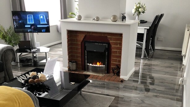 A modern living room with a fireplace, a flat-screen TV, and a dining area.