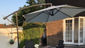 An outdoor patio with a table and chairs, a large umbrella, and a brick wall.