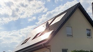 A residential building with a sloped roof, multiple windows, and a paved driveway. - Ferienwohnung Rieslingfreude - Erleben Sie Freude bei Freunden! (Rüdesheim am Rhein)