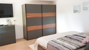 A bedroom with a bed, a wardrobe, a desk, and a television. - Ferienwohnung Rieslingfreude - Erleben Sie Freude bei Freunden! (Rüdesheim am Rhein)