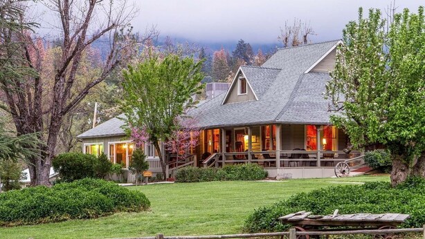 A large house with a porch, surrounded by a well-maintained lawn and trees. - Sierra Sky Ranch (Oakhurst)