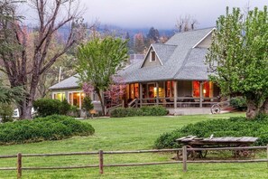 A large house with a porch, surrounded by a well-maintained lawn and trees. - Sierra Sky Ranch (Oakhurst)
