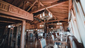 A rustic dining area with wooden beams, chandeliers, and vintage furniture. - Sierra Sky Ranch (Oakhurst)