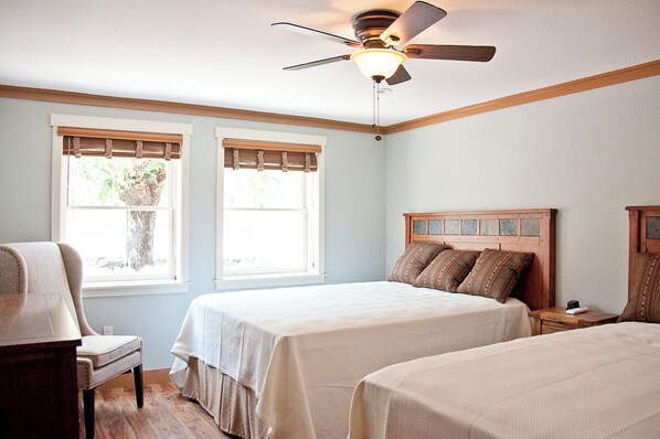 A bedroom with two beds, a ceiling fan, and a window with a view of a tree. - Sierra Sky Ranch (Oakhurst)