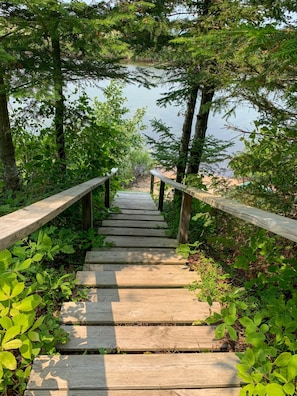 Stroll down to the serene water's edge, surrounded by lush greenery and trees.