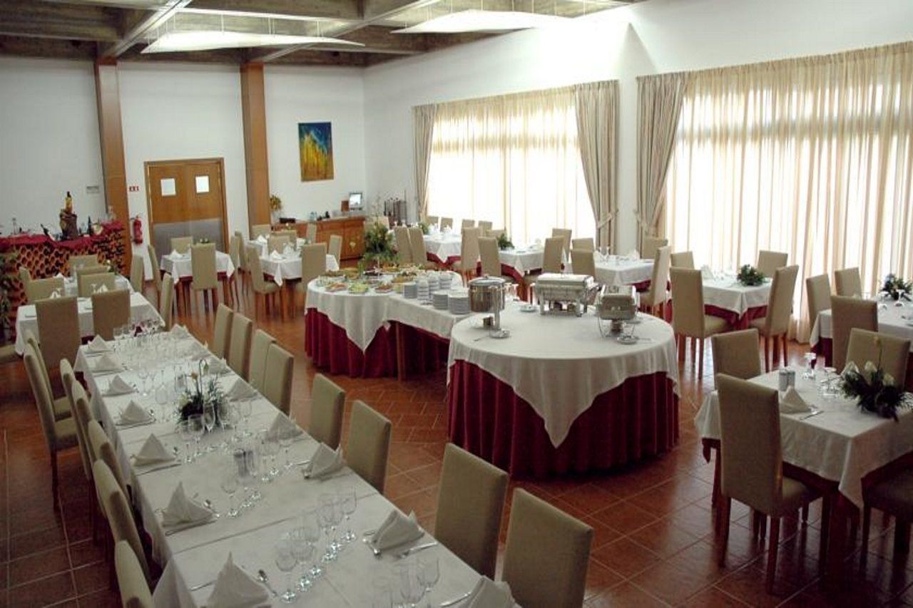 A banquet hall with multiple round tables, each set with white tablecloths and chairs.