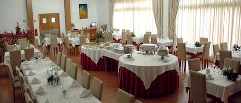 A banquet hall with multiple round tables, each set with white tablecloths and chairs.