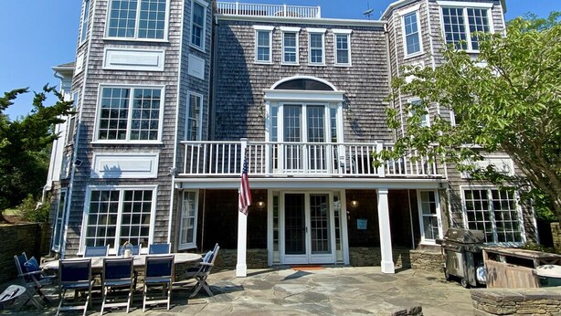 Una casa a due piani con un balcone, un patio con sedie e una bandiera americana.