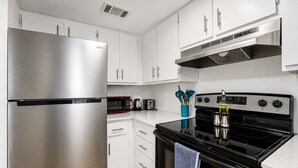Een moderne keuken met roestvrijstalen apparatuur, witte kasten en een zwart fornuis.