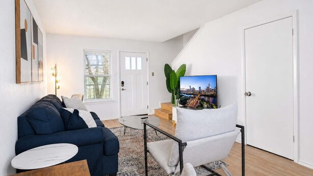 Een moderne woonkamer met een bank, een salontafel, een televisie en een trap naar een hoger niveau.