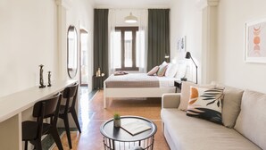 Ein modernes Schlafzimmer mit einem Bett, einem Sofa, einem Schreibtisch und Stühlen.
