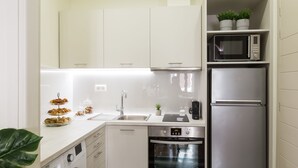 Eine kleine Küche mit Waschmaschine, Backofen, Mikrowelle und Kühlschrank.