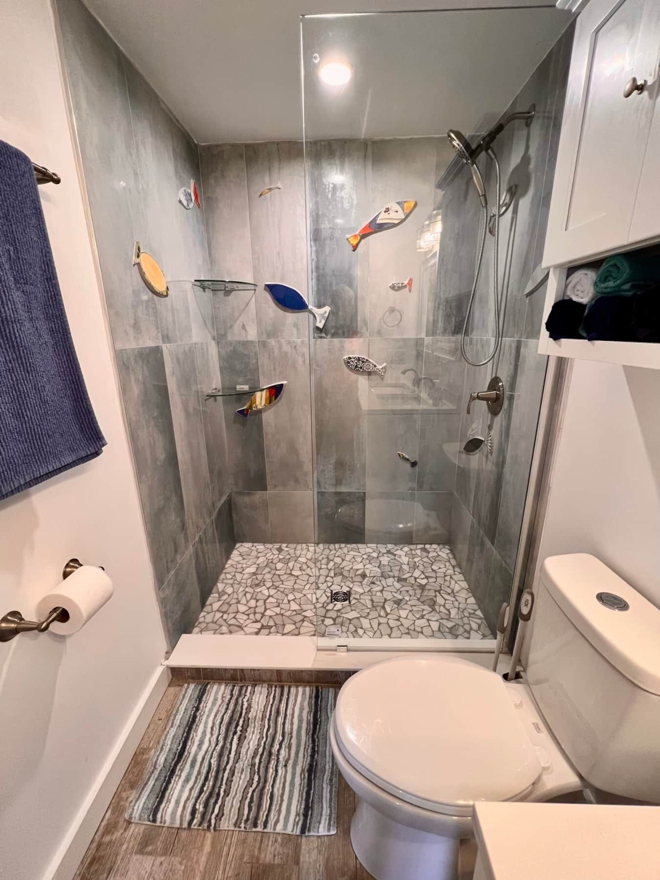 Kylpyhuone, jossa on lasiseinällä varustettu suihku, wc ja pesuallas.