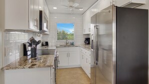A modern kitchen with white cabinets, stainless steel appliances, and a granite countertop. - Belleview Gulf Studio/Steps away from BEACH (378) (Indian Shores)
