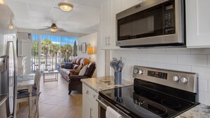 A modern kitchen with white cabinets, a stainless steel microwave, and a black stove. - Belleview Gulf Studio/Steps away from BEACH (378) (Indian Shores)