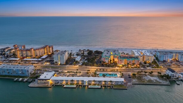 An aerial view of a coastal hotel area with multiple buildings, a marina, and a beach. - Belleview Gulf Studio/Steps away from BEACH (378) (Indian Shores)