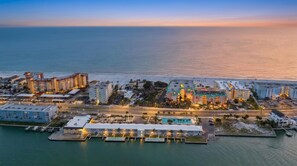 Eine Vogelperspektive auf einen Küstenhotelkomplex mit mehreren Gebäuden, einem Hafen und einem Strand.