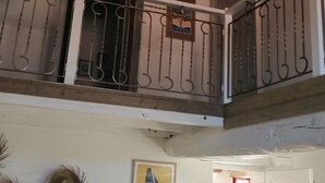 A balcony with wicker hanging lamps, a white railing, and a poster on the wall.