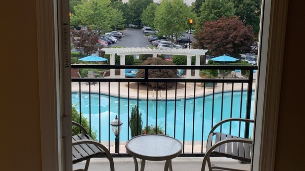 A balcony with a view of a swimming pool, two chairs, and a table. - Fabulous One Bed/One Bath Corporate Furnished Apt in Alpharetta (Alpharetta)