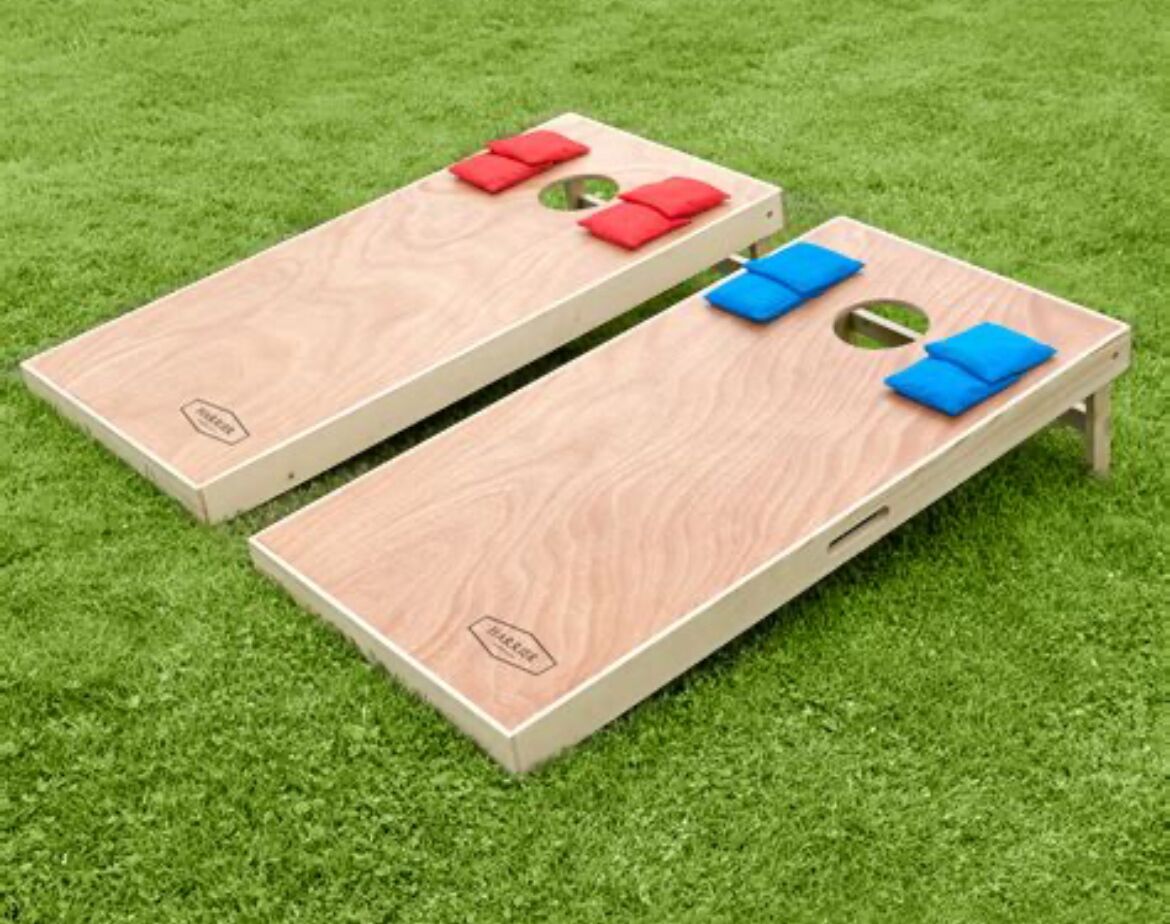 Zwei Holzbrettspiele auf einer grünen Rasenfläche.