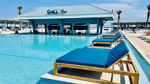 Un espace piscine avec des chaises longues et un bar décontracté.