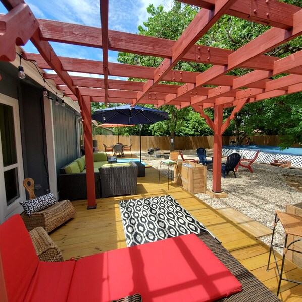 A covered patio area with outdoor furniture, a pool, and a wooden deck.
