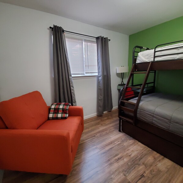 A room with a bunk bed, a sofa, a window with curtains, and a nightstand with a lamp. - Party with a Jaccuzzi, Firepit and Backyard Games for 12+ (Austin)