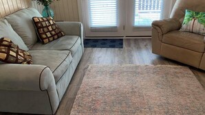 A living room with a beige sofa, a patterned rug, and a potted plant. - Beach house with pool only steps from the ocean (Murrells Inlet)
