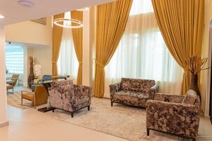A spacious living room with two patterned sofas, a coffee table, and a large window with curtains.