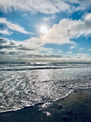 A beach with waves and a partly cloudy sky.