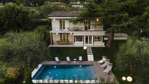 Ein zweistöckiges Haus mit Swimmingpool, Sitzgelegenheiten im Freien und Blick auf die umliegende Landschaft.