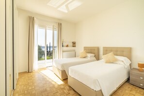 Une chambre avec deux lits, une table de chevet et une vue sur l’extérieur.