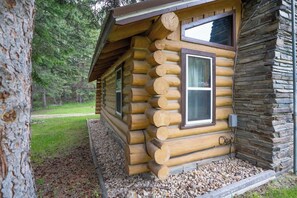 A log cabin with a stone exterior, a window with a white frame, and a door.