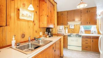A kitchen with wooden cabinets, a stainless steel sink, a stove, and a microwave.