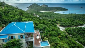 A house with a blue roof, a wooden deck, and a swimming pool.