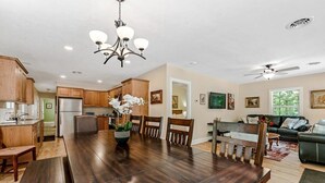 A spacious living area with a dining table, wooden cabinets, and a kitchen in the background. - Secluded Woodland Home with Trail and Lake Access (Pullman)