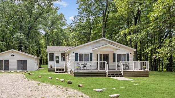 A two-story mobile home with a porch and a separate garage, surrounded by a forested area. - Secluded Woodland Home with Trail and Lake Access (Pullman)