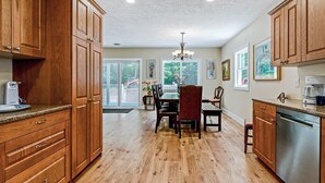 A kitchen with wooden cabinets, a dining table with chairs, a chandelier, and a dishwasher. - Secluded Woodland Home with Trail and Lake Access (Pullman)
