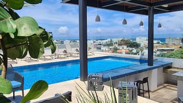 A rooftop pool with lounge chairs and a view of the cityscape.