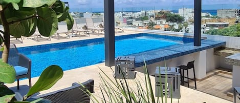 A rooftop pool with lounge chairs and a view of the cityscape.
