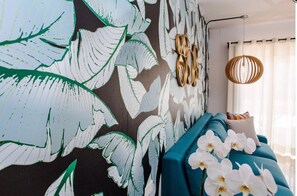 Relax in a stylish living room with a vibrant wall mural, a comfortable sofa, and a decorative wall piece.