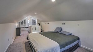 A bedroom with a large bed, a desk, and a chair in the corner.