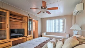 Camera da letto con un letto, una TV, un armadio, una ventola a soffitto, una finestra con persiane e un condizionatore.