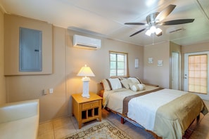 Une chambre à coucher comprenant un lit, une table de chevet, une lampe, un ventilateur de plafond et un appareil de climatisation.