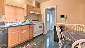 Una cucina con mobili in legno, un piano cottura, una lavastoviglie e un'area pranzo con tavolo e sedie.
