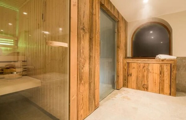 Eine Holzsauna mit Glastür, einer Sitzbank und einem kleinen Tisch mit einem Handtuch.